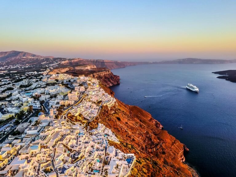 Stunning aerial shot of Santorini coast at sunset with a cruise ship in the Aegean Sea.