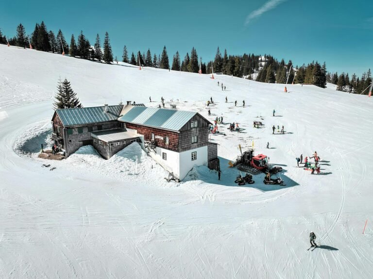 A picturesque winter scene at a ski resort in Hinterstoder, Austria, with skiers and a snow-covered lodge.