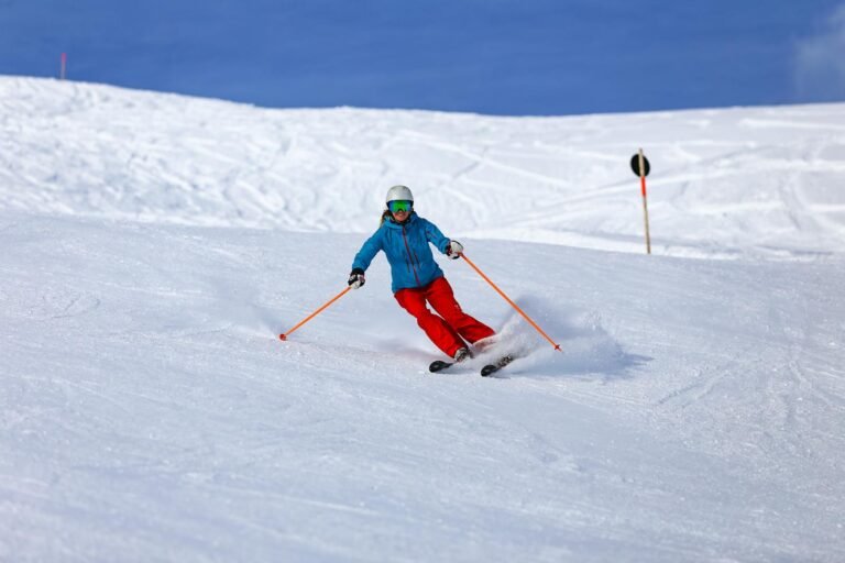 A skier in vibrant gear enjoys the snowy slopes of Vorarlberg, Austria, showcasing winter sports action.