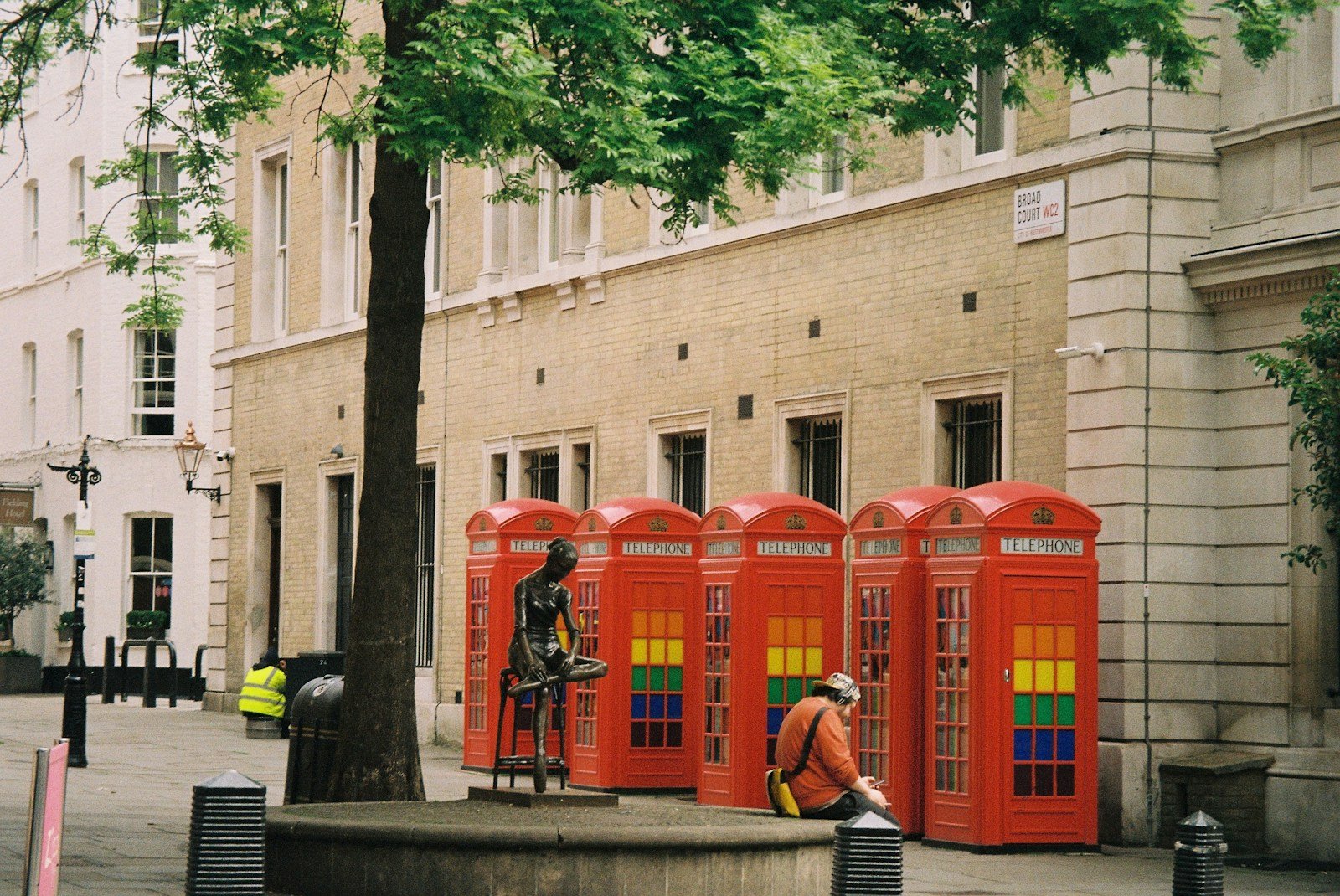 a group of red phone booths sitting next to a tree