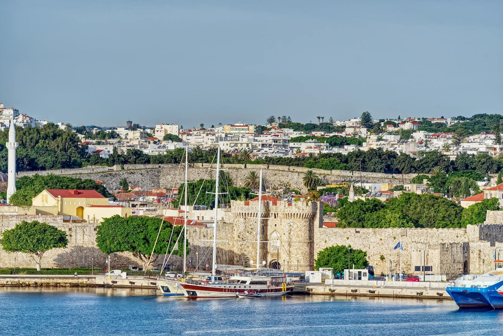 Picturesque view of Rhodes, featuring the medieval castle and a tranquil harbor with yachts.